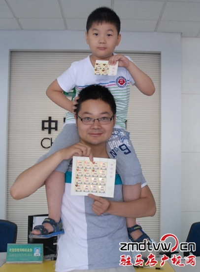圖為6月13日，一對父子在市中心郵政所展示“感恩父親”特種郵票 .JPG
