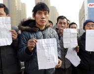 承建商已將工程款給付90%，但包工頭宋林卻把錢拿走不給工人結(jié)工資。一氣之下，十多名工人將包工頭車和人扣下，一不留神卻讓包工頭翻墻跑了。2015年12月31日，在勞動(dòng)監(jiān)察部門協(xié)調(diào)下達(dá)成初步協(xié)議，包工頭將工人手續(xù)移交到成泰公司，由成泰公司替宋林代付一半工資，但在移交工人手續(xù)的時(shí)候包工頭害怕再次被扣卻一直不敢露面。1月3日，包工頭給農(nóng)民工發(fā)來(lái)短信，并要求寫(xiě)下承諾書(shū)，保證不扣他本人。圖為1月5日，陜西商洛，討薪農(nóng)民工在工地上出示欠條和他們寫(xiě)給包工頭的承諾書(shū)。華商報(bào)記者 閆文青/視覺(jué)中國(guó)