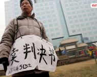 2006年1月24日，在京從事降水井工程的老陳掛著寫(xiě)有“賣判決書(shū)”的紙口袋在北京站口附近來(lái)回走著。曾是名小工頭的老陳被欠工程款4萬(wàn)元，為了給工人們開(kāi)資不得已賣掉了打井機(jī)器。2002年法院宣判老陳勝訴，可四年后該判決仍得不到執(zhí)行，無(wú)奈之中老陳只好上演此幕。程寧/視覺(jué)中國(guó)